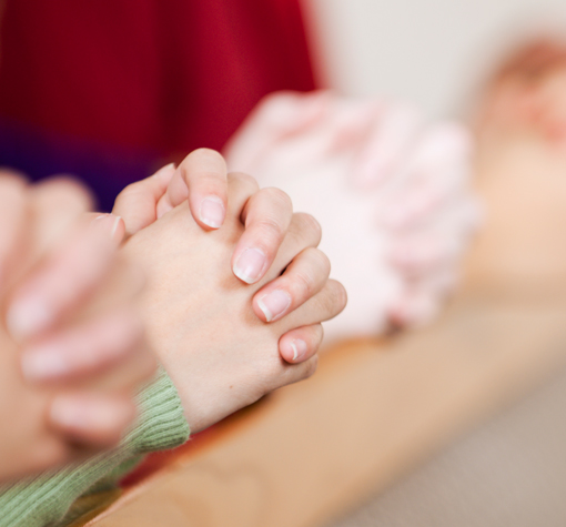 hands clasped in prayer on a church pew